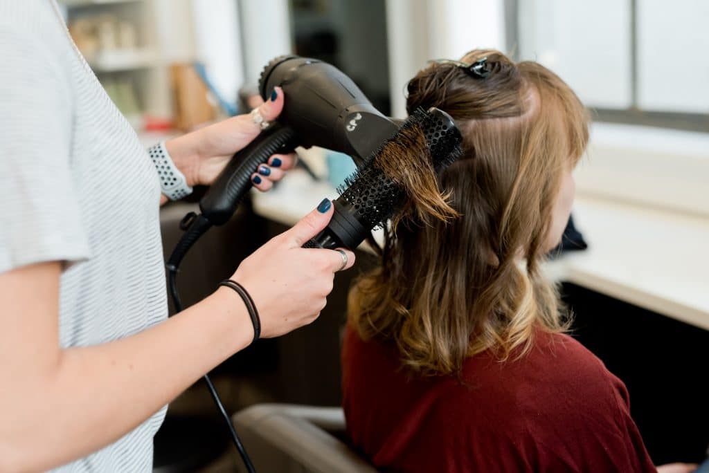 A woman having her hair blow dryed and curled inside Fringe salon and spa.